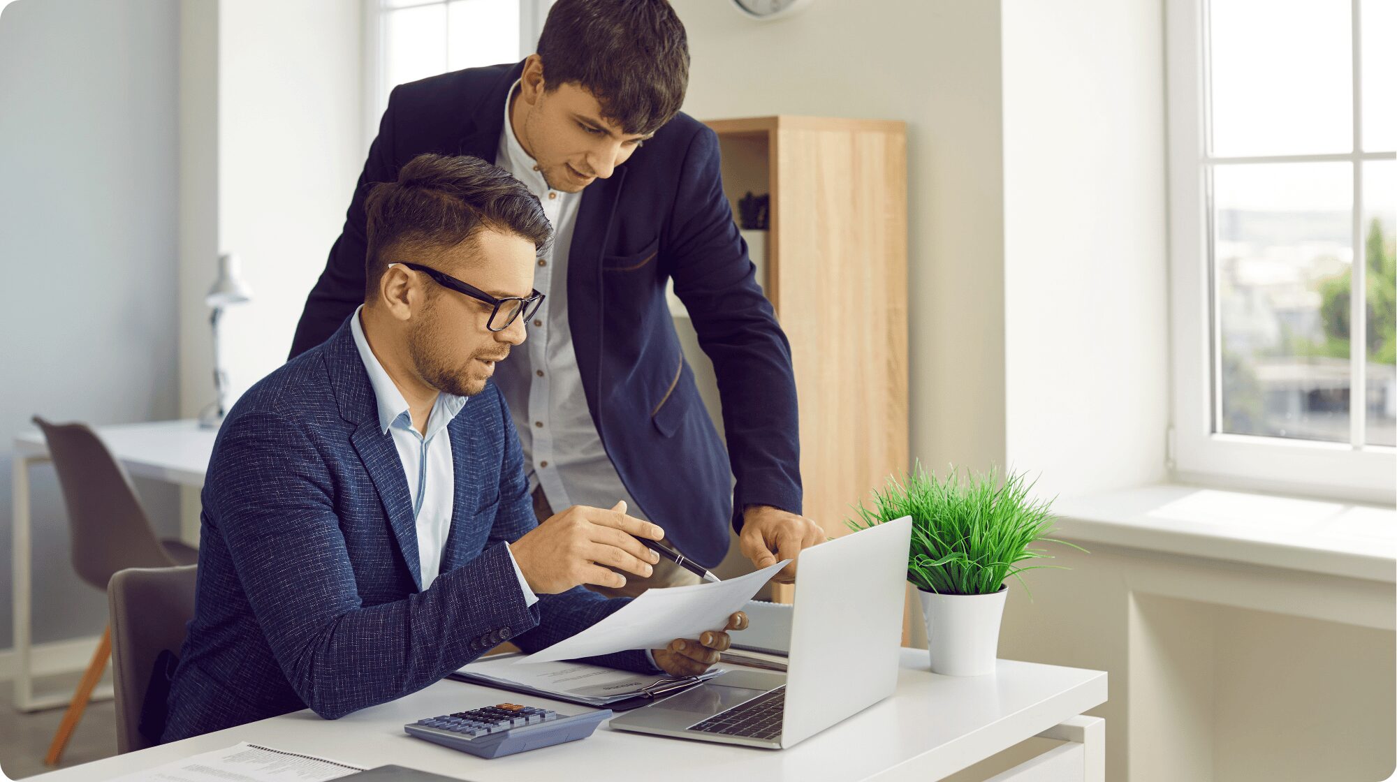 Two male colleagues in suits reviewing a report document