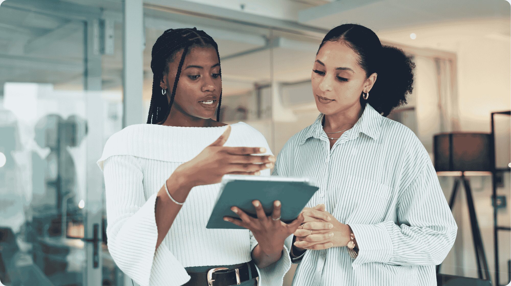 Two women stood up discussing a document they are both looking at.